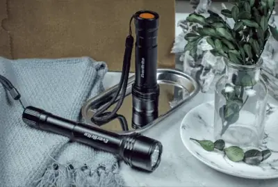 two flashlights on a table next to a blanket and a vase