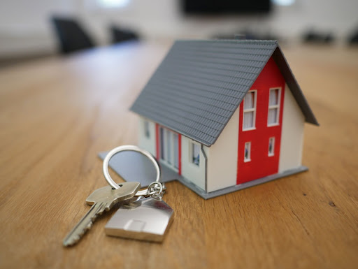 A key on a keyring in front of a miniature model house.